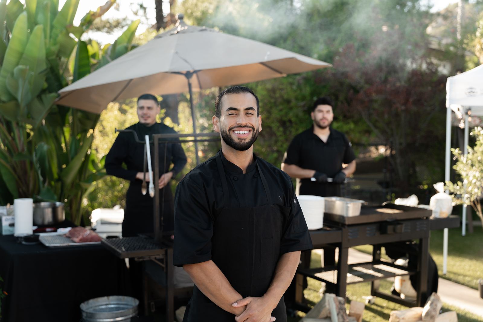Chef Edgar Meza smiling at his live-fire grill station