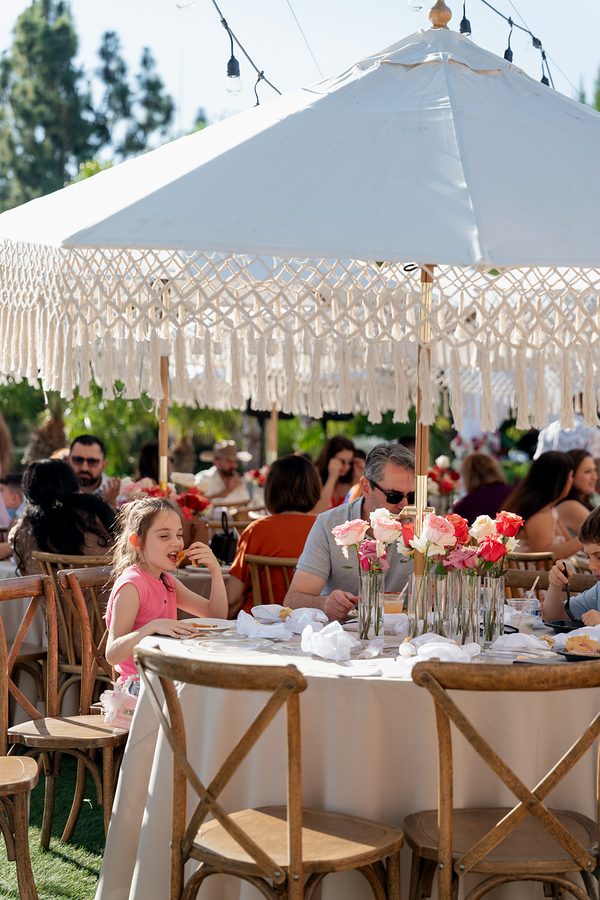 Guests at a garden celebration under white umbrellas
