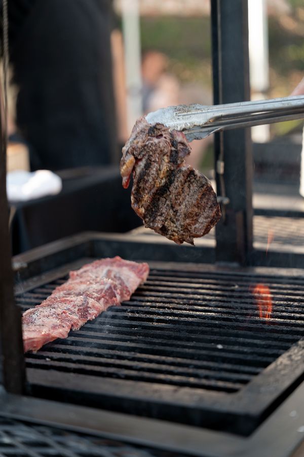 Lifting a charred steak off the Santa Maria grill